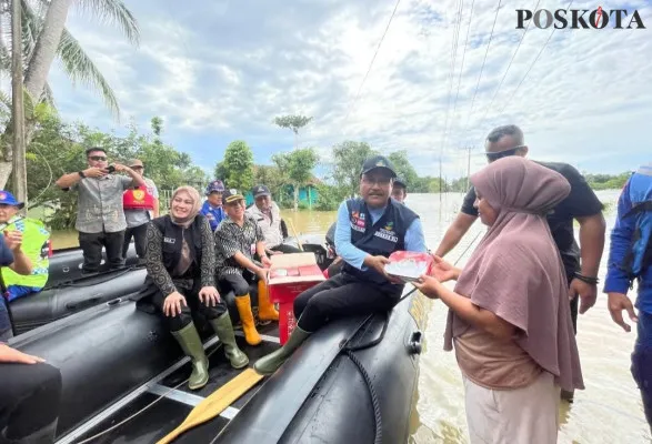 Dari atas perahu, Menteri Sosial Saifullah Yusuf saat membagikan logistik kepada korban banjir di Desa Sukadame, Kecamatan Pagelaran, Pandeglang, Jumat, 6 Desember 2024. (Poskota/Samsul Fatoni)