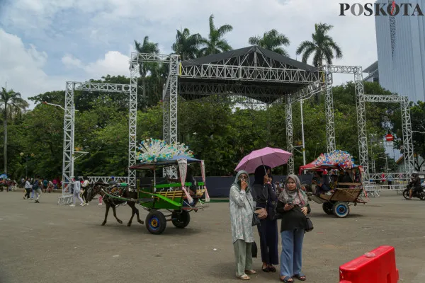 Aktivitas pekerja saat menyelesaikan pembangunan panggung hiburan rakyat di beberapa titik yang disaksikan oleh sejumlah pengunjung di kawasan Monumen Nasional (Monas) di Jakarta, Minggu, 29 Desember 2024. ( Poskota/ Ahmad Tri Hawaari)