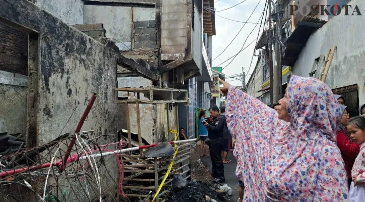 Ketua RT 012 RW 05, Siti Komariah menunjuk lokasi lantai dua rumah yang terbakar dan ditemukan keluarga bapak Agam yang tewas terpanggang akibat kebakaran. (Poskota/Angga)