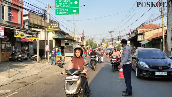 Petugas Dishub Kota Cimahi, melakukan pengaturan arus lalu-lintas di persimpangan Cibeber Cimahi Selatan. (Poskota/Gatot Poedji Utomo)