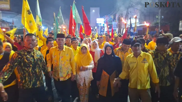 Uu Saeful Mikdar (batik kuning dan kopiah hitam) dan Nurul Sumarhaeni (jilbab biru) diiringi pawai obor saat menuju Kantor KPU Kota Bekasi mendaftar Pilkada 2024. (Poskota/Ihsan)