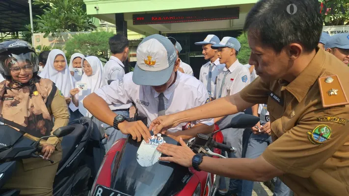 Salah satu perwakilan Samsat saat menempelkan stiker ke kendaraan milik siswa di SMAN 1 Kota Bekasi. (Poskota/Ihsan)