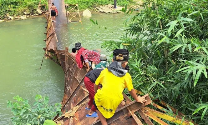 Sejumlah warga di Desa Parakanbeusi, Kecamatan Bojongmanik, Kabupaten Lebak saat melintasi jembatan ambruk. (Dok. Warga)