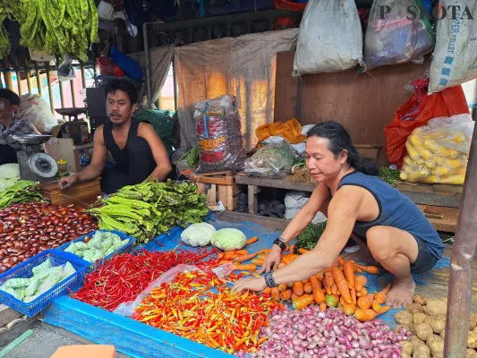 Sofyan, pedagang sayur mayur saat merapihkan cabai rawit di lapak miliknya, Senin, 30 Desember 2024. (Poskota/Ihsan).