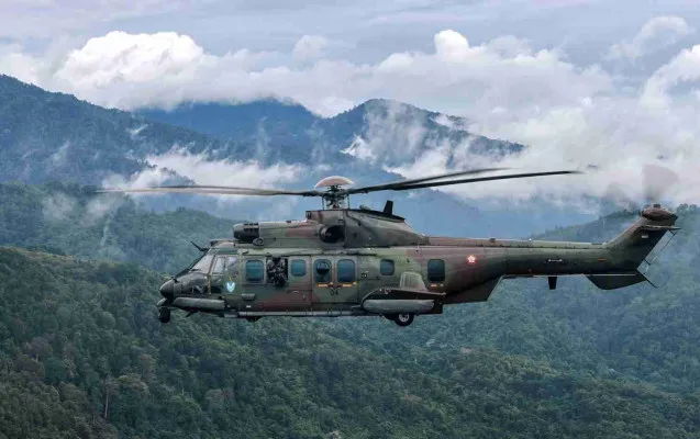 Seorang prajurit TNI AU siaga dengan senapan mesin di helikopter Airbus H225M (EC 725 Caracal) saat melintasi kawasan pegunungan. (tni-au.mil.id)