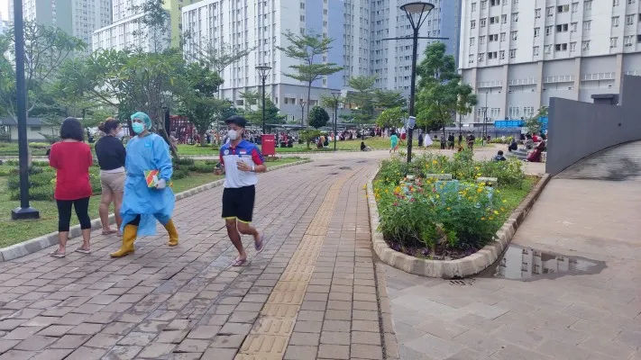 Pasien isolasi Covid-19 sedang melakukan kegiatan olahraga lari dan jalan sore di RSDC Wisma Atlet Kemayoran, terlihat juga tenaga kesehatan yang bertugas. Foto : poskota.co.id, Firas Dalil