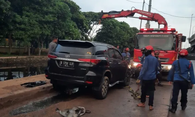 Petugas pemadam kebakaran saat melakukan evakuasi kendaraan yang tercebur ke kali. Ist)