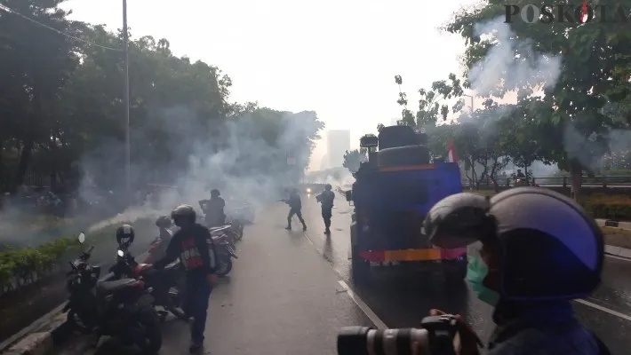 Polisi pukul mundur massa aksi yang masih berada di depan Gedung DPR dengan menembakana gas air mata. (foto: poskota/ pandi)