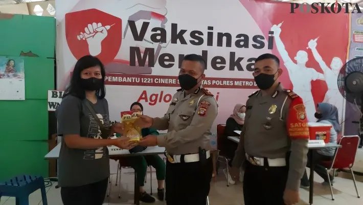 Wakasat Lantas Polres Metro Depok, Kompol David Purba didampingi Kasubnit Satpas SIM Cinere, Iptu Toni memberikan migor kepada warga usai vaksin booster. (foto: poskota/ Angga)