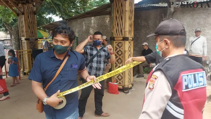 Petugas Polsek Bojongsari memasang garis polisi di lokasi tenggelamnya balita di kolam renang THI Depok. (foto: poskota/ angga)