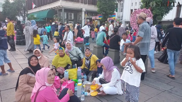 Siti Maryam (43) dan keluarga saat berada di kawasan wisata Kota Tua. (foto: poskota/pandi ramedhan)