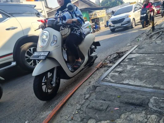 Kabel fiber optik yang melintang di permukaan di Jalan Kebon Jeruk Raya, Jakarta Barat, dikeluhkan warga. (Poskota/Pandi)