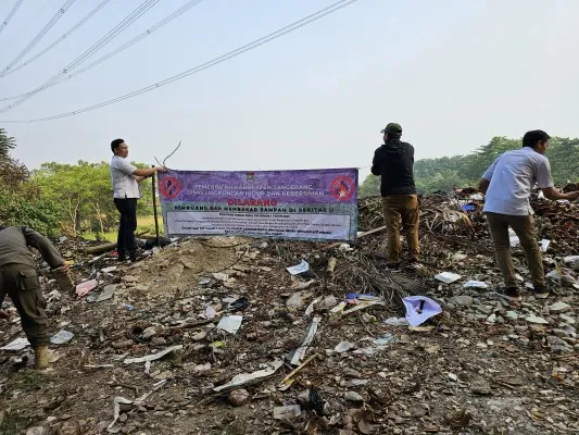 Petugas DLHK saat memasang spanduk larangan di lokasi TPS liar. (sumber: dok. Pemkab Tangerang)