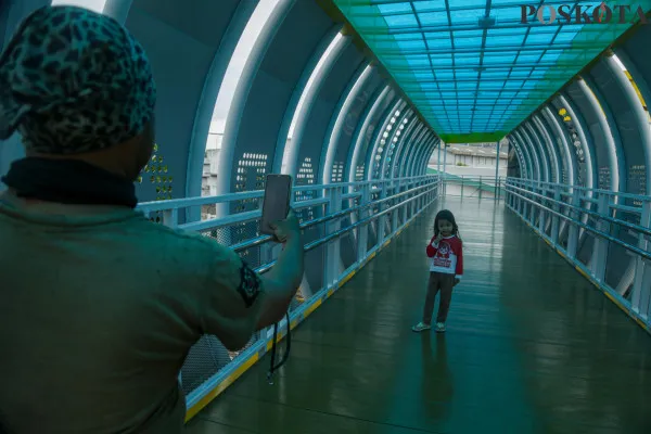 Warga saat melintasi Jembatan Penyeberangan Orang (JPO) Sunter Muara, Sunter, Jakarta Utara, Rabu, 18 Desember 2024. (Poskota/ Ahmad Tri Hawaari)