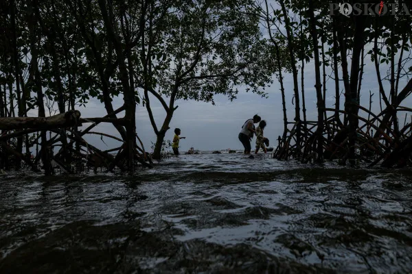 Sejumlah warga menikmati suasana pantai dengan berbagai aktivitas seperti berjalan di sisi pantai, berfoto hingga berenang di tengah banjir rob yang masih melanda di kawasan Pantai Marunda, Jakarta Utara, Kamis, 26 Desember 2024. (Poskota/ Ahmad Tri Hawaari)