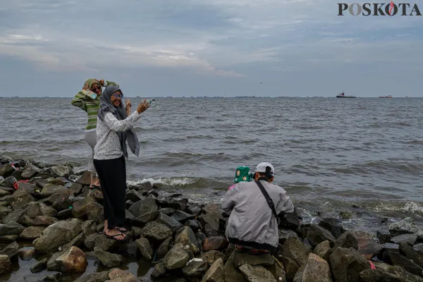 Sejumlah warga menikmati suasana pantai dengan berbagai aktivitas seperti berjalan di sisi pantai, berfoto hingga berenang di tengah banjir rob yang masih melanda di kawasan Pantai Marunda, Jakarta Utara, Kamis, 26 Desember 2024. (Poskota/ Ahmad Tri Hawaari)