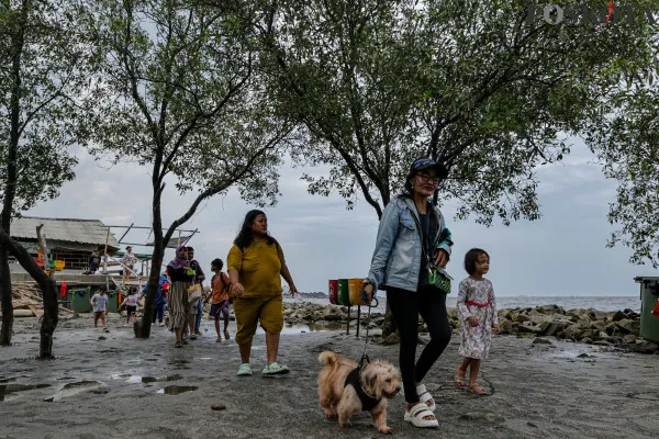 Sejumlah warga menikmati suasana pantai dengan berbagai aktivitas seperti berjalan di sisi pantai, berfoto hingga berenang di tengah banjir rob yang masih melanda di kawasan Pantai Marunda, Jakarta Utara, Kamis, 26 Desember 2024. (Poskota/ Ahmad Tri Hawaari)