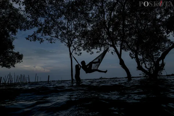 Sejumlah warga menikmati suasana pantai dengan berbagai aktivitas seperti berjalan di sisi pantai, berfoto hingga berenang di tengah banjir rob yang masih melanda di kawasan Pantai Marunda, Jakarta Utara, Kamis, 26 Desember 2024. (Poskota/ Ahmad Tri Hawaari)