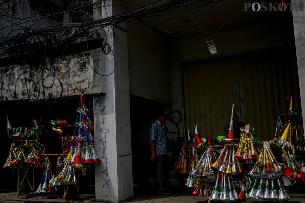 Pengrajin sekaligus pedagang saat menyelesaikan pembuatan terompet kertas sembari menunggu pembeli di Jalan Pintu Besar Selatan, Pancoran Glodok, Jakarta Barat, Jumat, 27 Desember 2024. (Poskota/ Ahmad Tri Hawaari)