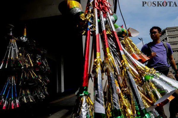 Pengrajin sekaligus pedagang saat menyelesaikan pembuatan terompet kertas sembari menunggu pembeli di Jalan Pintu Besar Selatan, Pancoran Glodok, Jakarta Barat, Jumat, 27 Desember 2024. (Poskota/ Ahmad Tri Hawaari)