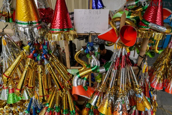 Pengrajin sekaligus pedagang saat menyelesaikan pembuatan terompet kertas sembari menunggu pembeli di Jalan Pintu Besar Selatan, Pancoran Glodok, Jakarta Barat, Jumat, 27 Desember 2024. (Poskota/ Ahmad Tri Hawaari)