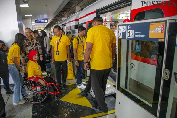 Petugas memandu penyandang disabilitas di Stasiun LRT Jakarta Velodrome, Rawamangun, Jakarta Timur, Selasa, 3 Desember 2024. (Poskota/ Ahmad Tri Hawaari)
