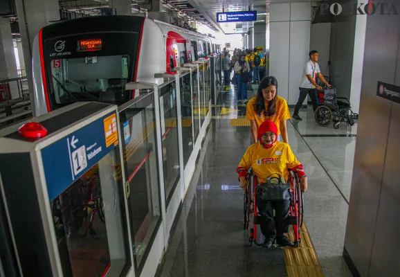 Petugas memandu penyandang disabilitas di Stasiun LRT Jakarta Velodrome, Rawamangun, Jakarta Timur, Selasa, 3 Desember 2024. (Poskota/ Ahmad Tri Hawaari)