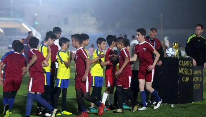 Anak-anak mengenakan kaus tim nasional Qatar dan Ekuador berjabat tangan sebelum pertandingan pembukaan "Camps World Cup" di Stadion Kota Idlib pada 19 November 2022.