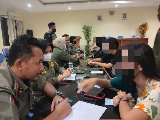 Foto : Petugas Satpol PP Kabupaten Bogor tengah memeriksa PSK yang terjaring. (Dok. Poskota)