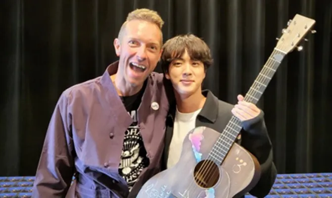 Chris Martin memberi Jin BTS sebuah gitar akustik dengan desain spesial. (Foto/twitter@BTS_twt) 