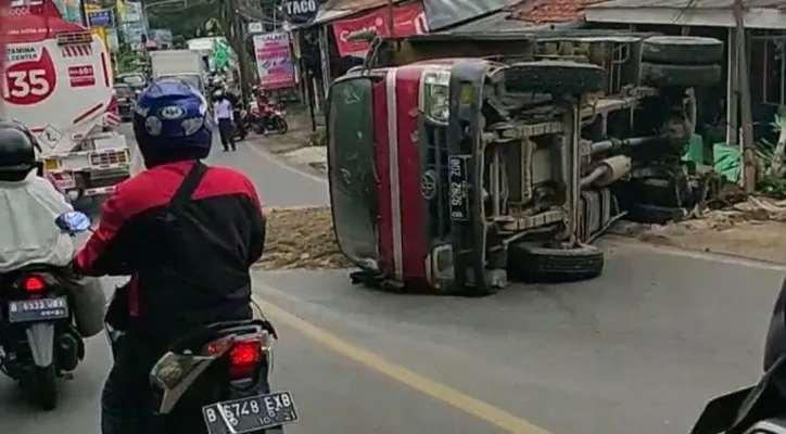 Kondisi truk pasir terguling dan isi muatan tumpah ke jalan. (ist)