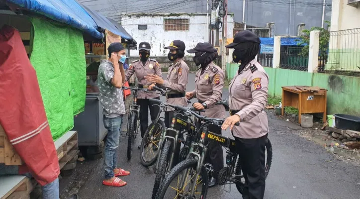 Polwan Ramadan melakukan patroli sepeda menegur hingga memberikan masker kepada seorang pejalan kaki yang mengabaikan protokol kesehatan. (foto: ist)