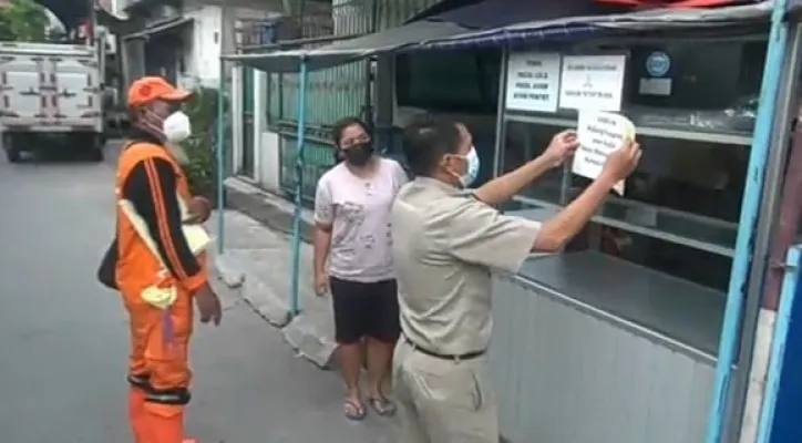 Lurah Pademangan Timur Bambang Mulyanto menempelkan stiker larangan mudik di permukiman warga. (yono)