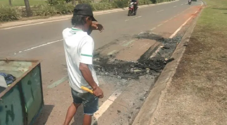 Pardi (42), pemulung, memunguti kawat tembaga bekas Toyota Rush yang terbakar di Gading Serpong, Tangerang, Selasa (11/05/2021). (foto: Ridsha Vimanda)