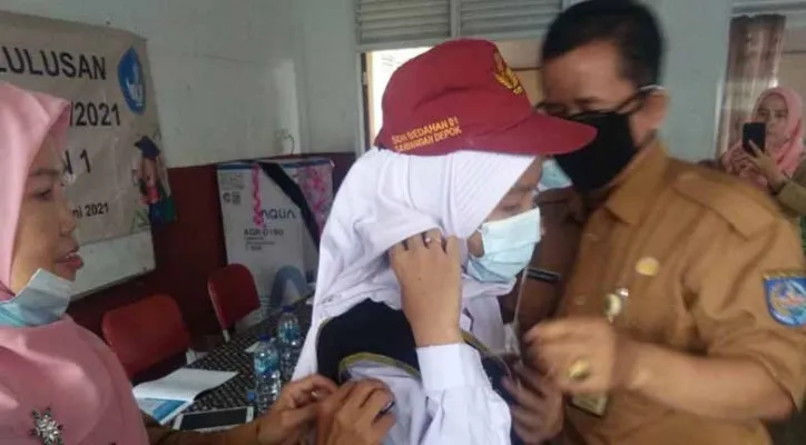 Kepala SDN Bedahan 01, Abdul Kholik (kanan) memberikan selempang kepada siswa berprestasi dalam kegatan kelulusan SD. (ist)