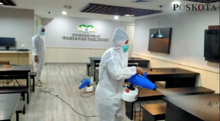 Petugas sedang melakukan penyemprotan disinfektan untuk sterilisasi ruang wartawan di DPR. (foto: rizal)