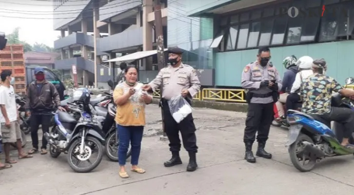 Anggota Polsek Cimanggis membagikan masker kepada pengendara motor dan pedagang pasar yang tidak bermasker. (Angga)