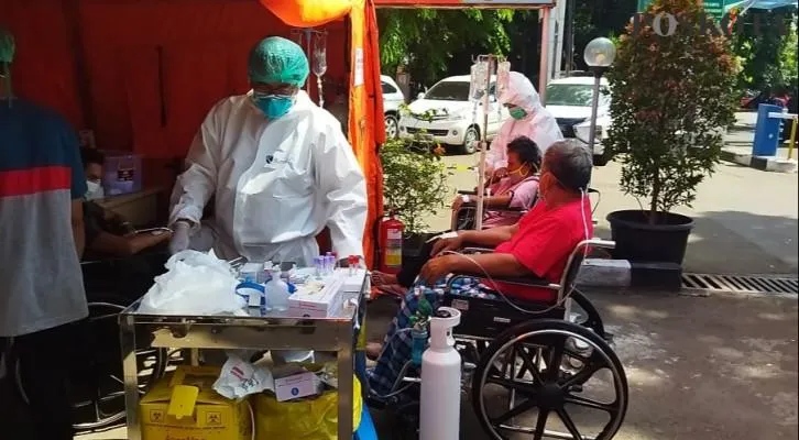 Tenaga kesehatan sedang merawat pasien di tenda triase darurat yang berdiri di lahan parkir RSUD Chasbullah Abdulmadjid Kota Bekasi, Jumat (25/6/2021). (foto: poskota/cr02)