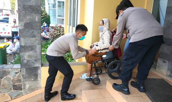 Petugas polisi membantu penyandang disabilitas mengikuti vaksinasi massal di Polres Tangerang Selatan. (Foto/Ridsha Vimanda)