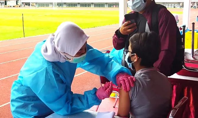 Salah seorang peserta vaksinasi masal COVID-19 sedang menjalani vaksin di Stadion Patriot Candrabhaga, Kamis 1 Junli 2021.(Foto/cr02)