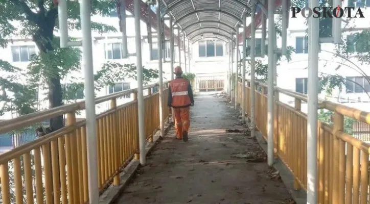 Sampah dan tumbuhan rambat yang mengotori Jembatan Penyebrangan Orang (JPO) Bandengan Indah di Jalan Bandengan Utara Raya, dan Selatan, Penjaringan, telah dibersihkan oleh petugas gabungan. (Foto/Poskota.co.id/Yono)