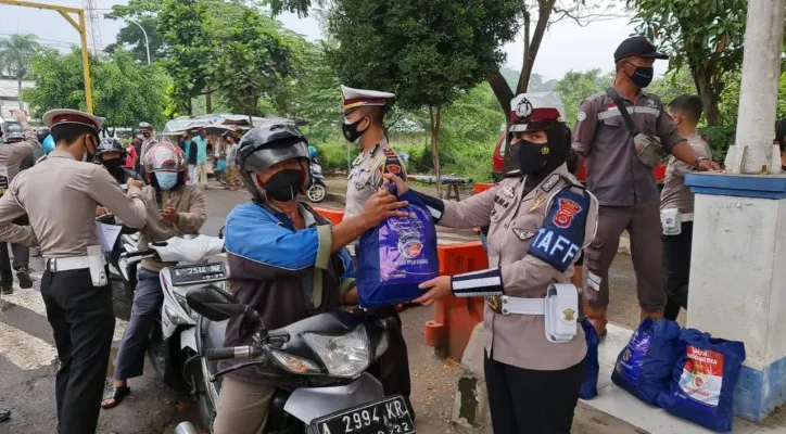 Tim Satuan Lalulintas Polres Lebak saat melakukan pembagian paket sembako bagi warga terdampak PPKM Level 4. (Foto/Humas Satlantas Polres Lebak)