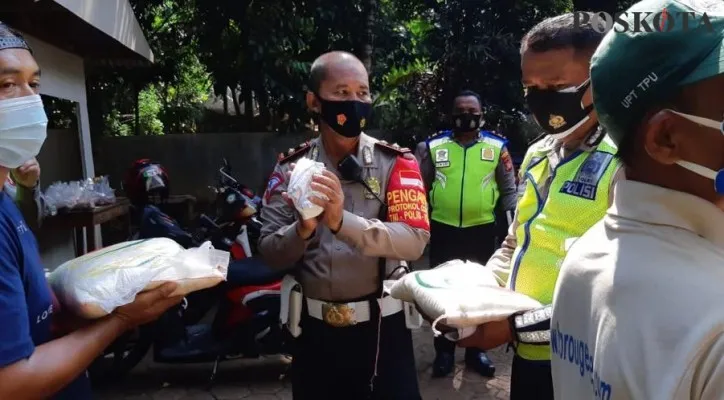 Wakasat Lantas Polres Metro Depok Kompol Sugeng didampingi Kanit Kamsel AKP Elly bersama anggota bagikan bansos kepada penjaga makam. (Foto/Poskota.co.id/Angga)