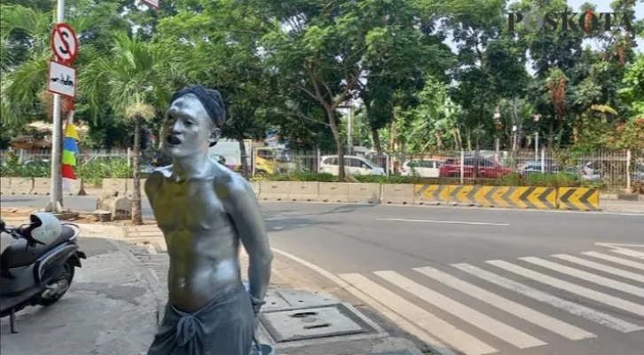 Manusia silver penyandang masalah kesejahteraan sosial (PMKS) saat sedang mengamen di lampu merah Jalan Panjang. (foto: Pandi).