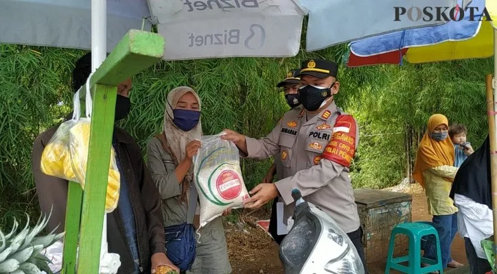 Kapolsek Sawangan AKP Meltha Mubarak bersama anggota bagikan paket sembako bagi masyarakat warga yang tertib protokol kesehatan penggunaan masker. (Foto/Angga)