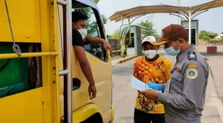 Petugas karantina saat melakukan dokumen truk yang mengangkut hasil pertanian dan hewan. (foto: ist)