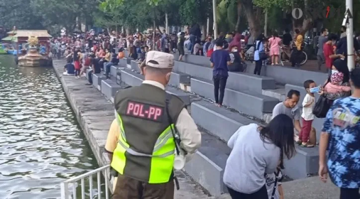 Petugas Satpol PP dari Kecamatan Tanjung Priok sedang memberikan imbauan pada warga untuk tidak berada di kawasan Danau Sunter supaya mengurangi kerumunan, Minggu (12/9/2021) sore. (foto: poskota/cahyono)