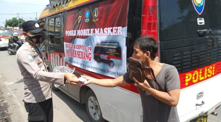 Personel Satbinmas memberikan masker kepada pengguna jalan melalui posko mobil masker. (foto: ist)