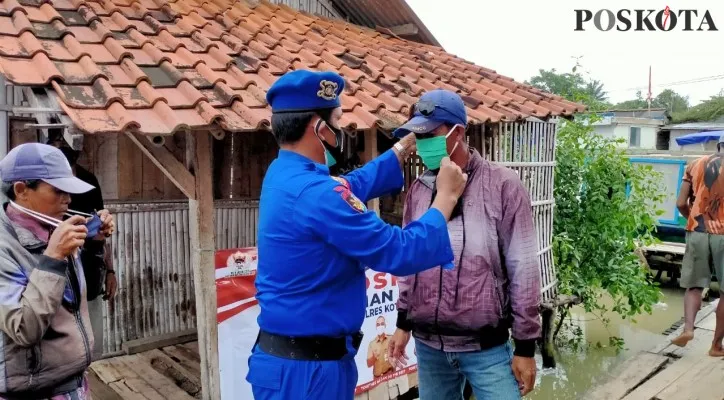 Anggota Satpolair Polresta Tangerang sedang membagikan dan memakaikan masker kepada salah satu warga pesisir Tangerang. (foto: ist)