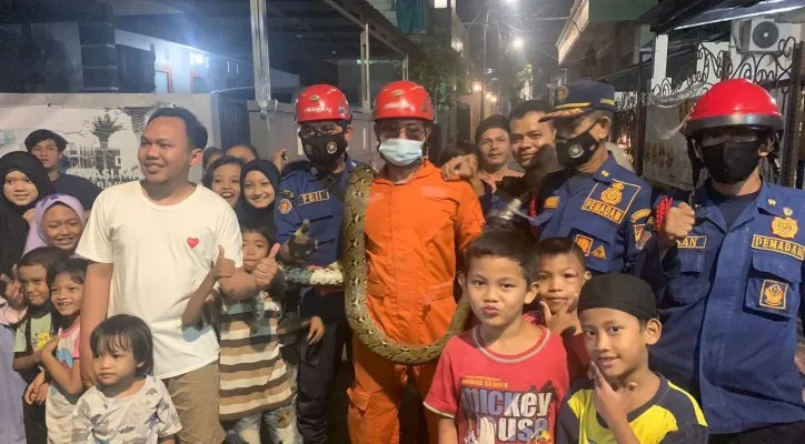 Warga berfoto bareng bersama ular yang dievakuasi Petugas Gulkarmat Pancoran. (Foto/Gulkarmat Pancoran)